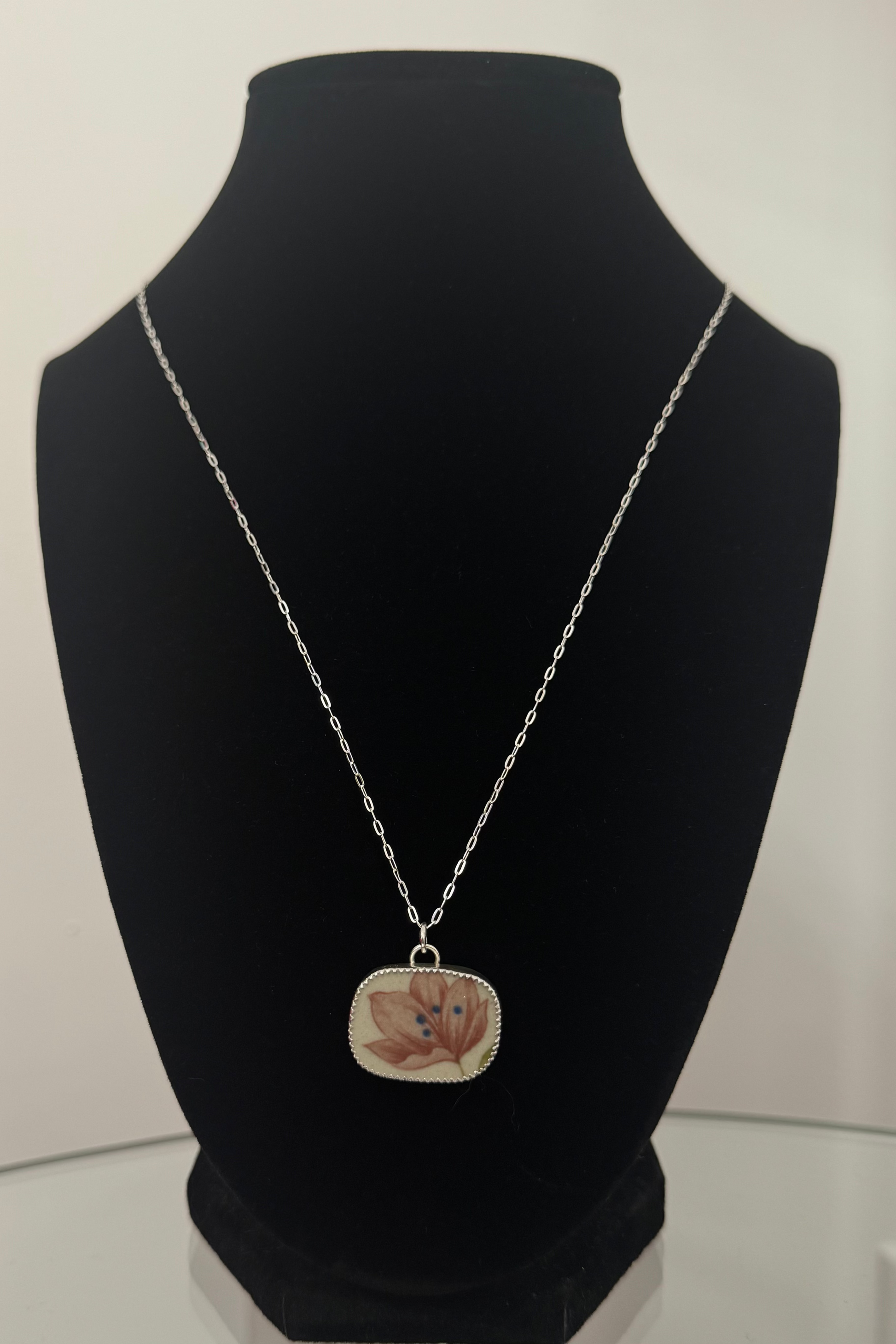 Necklace with a pendant on a black mannequin bust against a white background