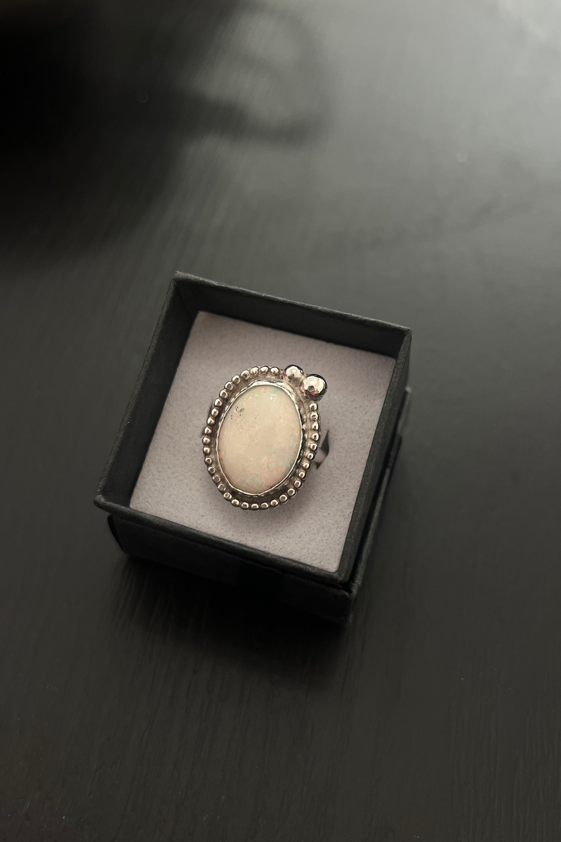 Silver ring with a stone in a black box on a dark surface