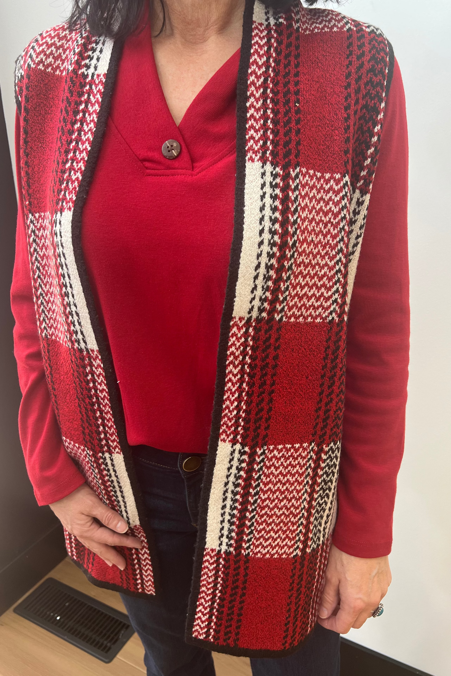 Person wearing a red cardigan with a patterned design over a red shirt.