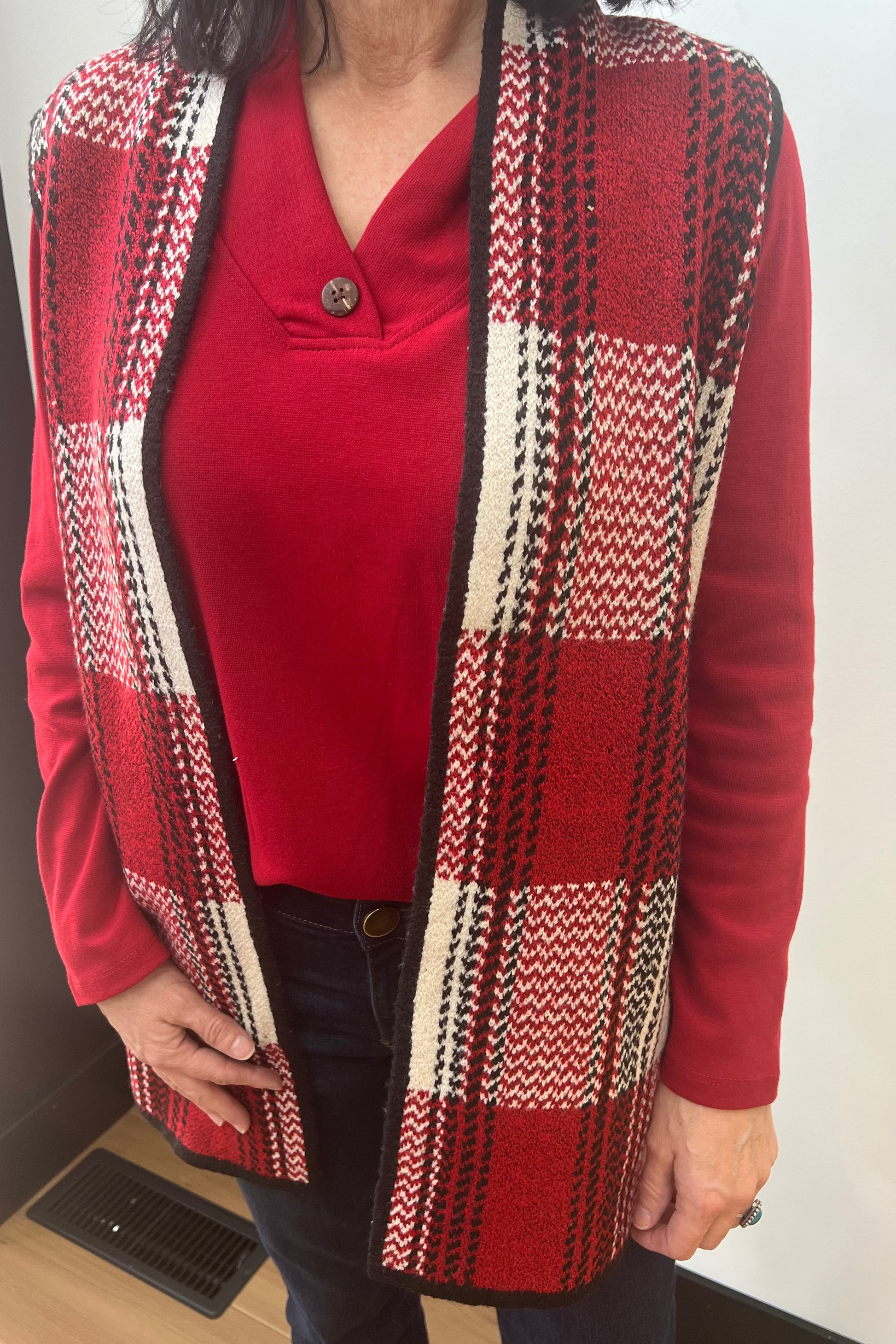 Person wearing a red cardigan with a patterned design over a red shirt.