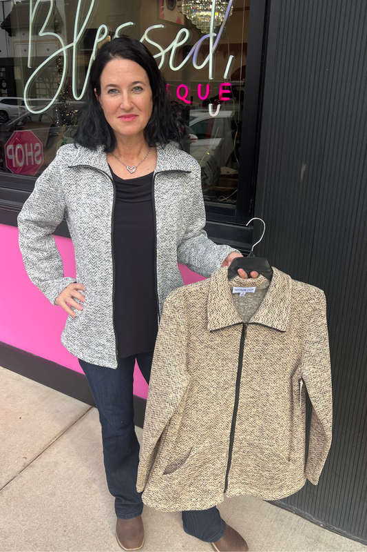 Woman holding a beige jacket in front of a store with 'Simply Blessed' sign.