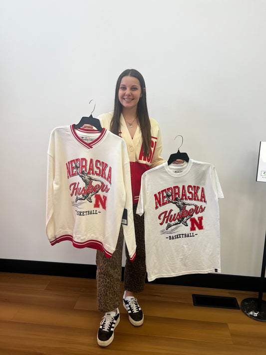 Person standing next to a table with multiple 'Nebraska' branded bags on a white background