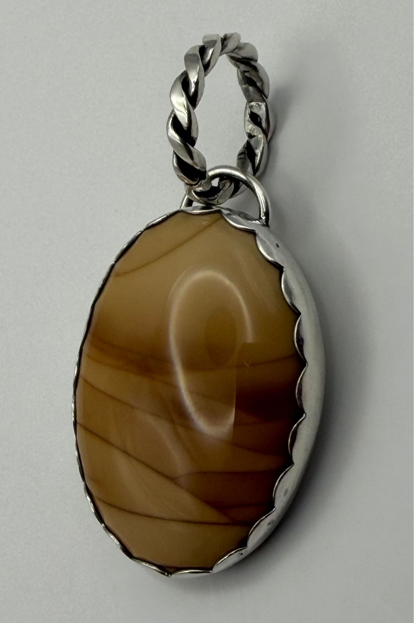 side view of pendant, with a scalloped border.