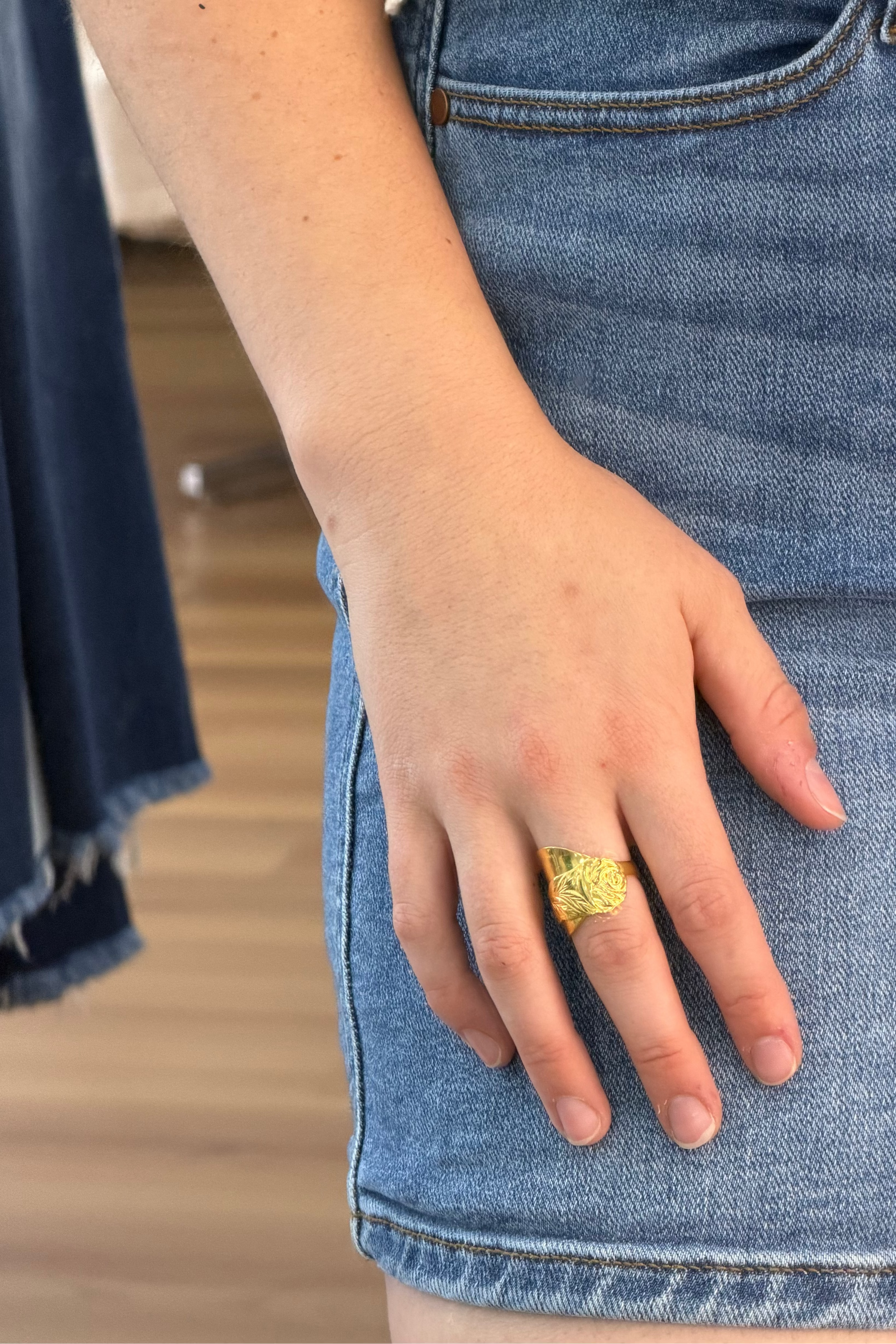Gold ring shown on hand against jeans