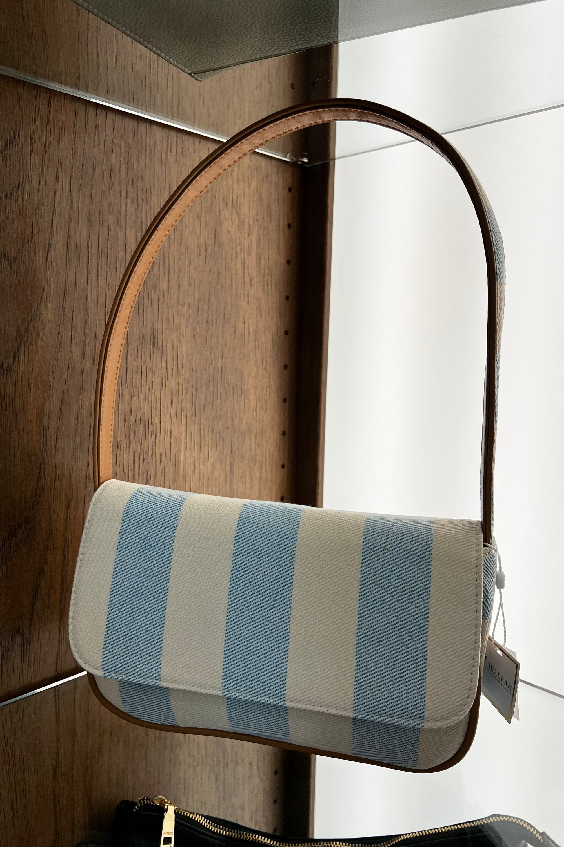 Striped handbag with a wooden handle on a wooden surface