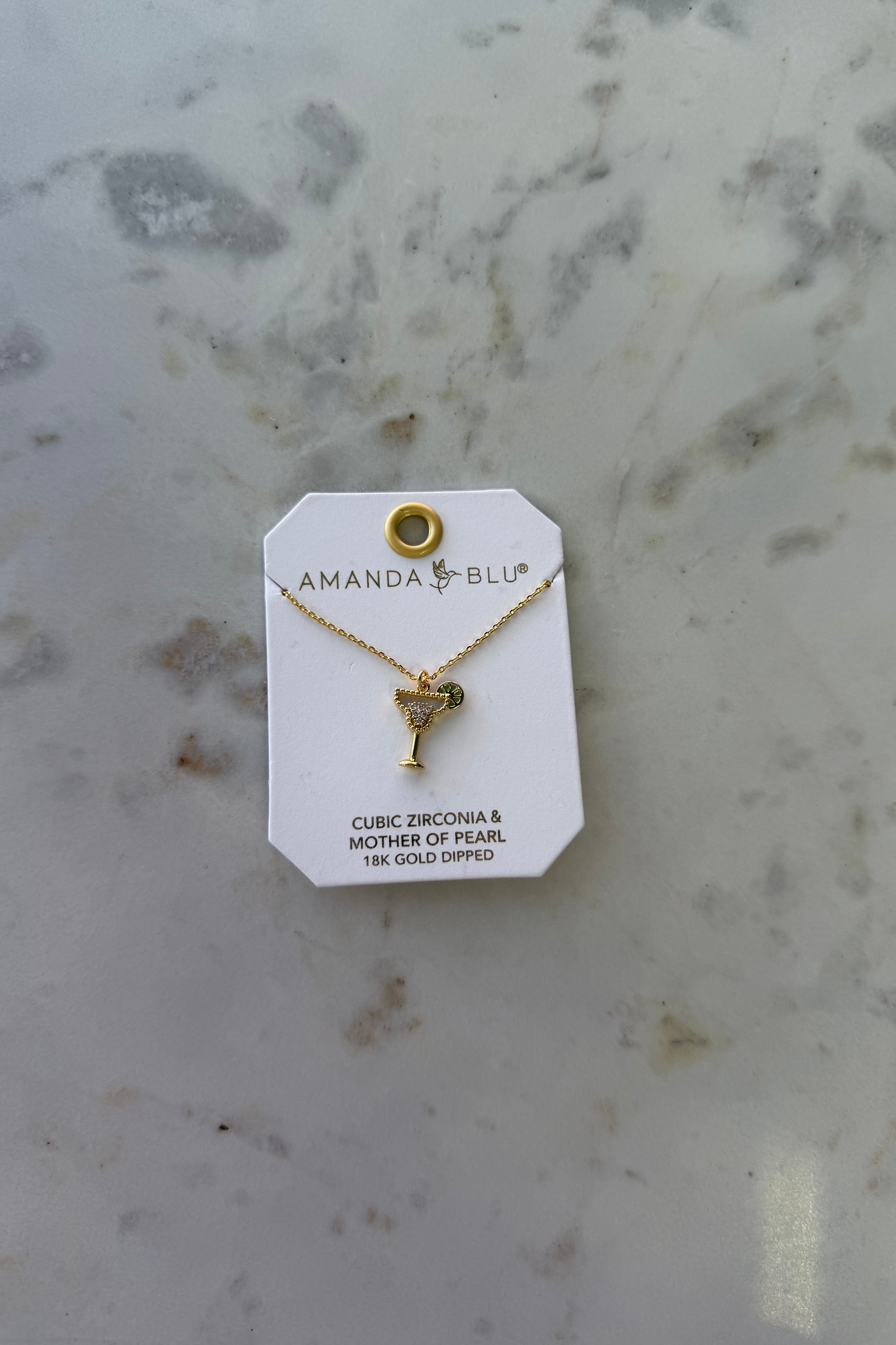 Gold necklace with a martini against a marble background