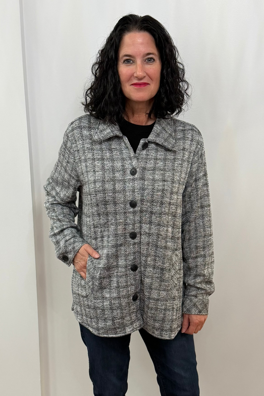 Woman wearing a checkered coat standing against a white curtain