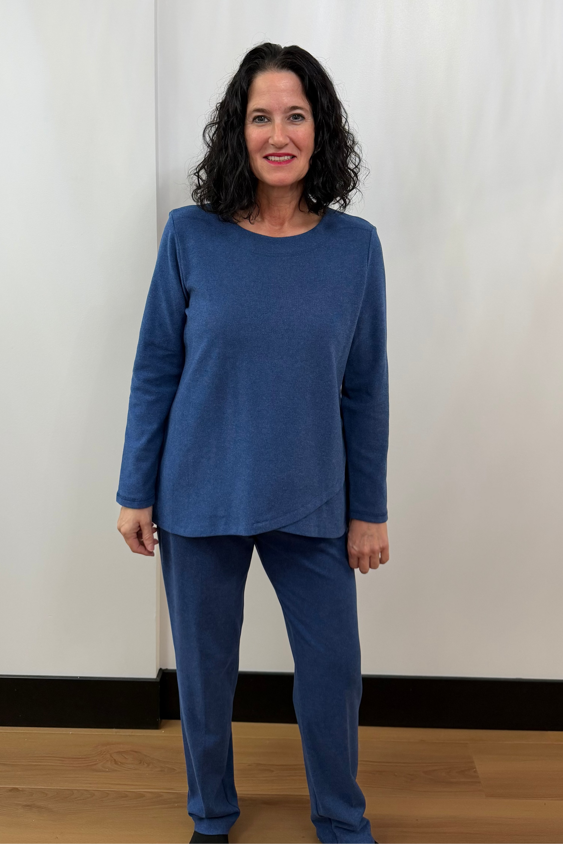 Woman wearing a blue outfit standing against a white curtain background