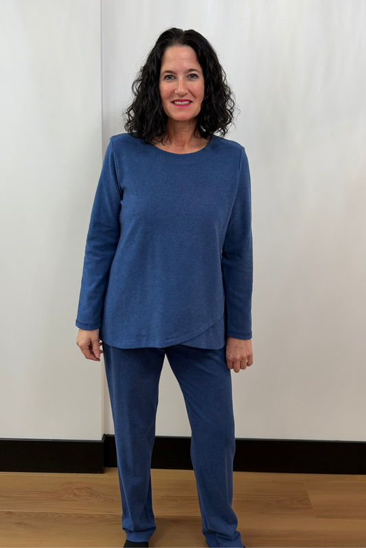 Woman wearing a blue outfit standing against a white curtain background