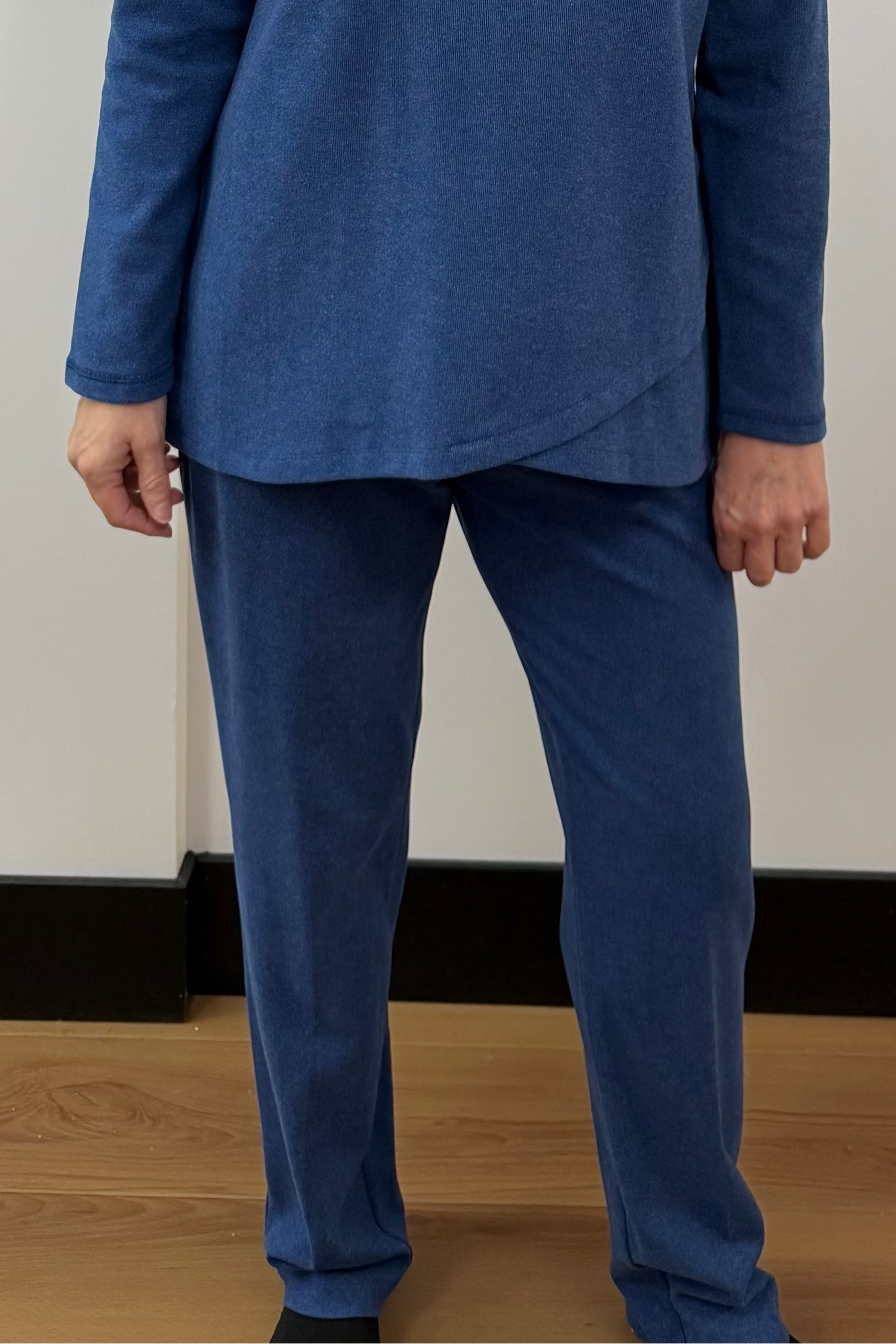 Woman wearing a blue outfit standing against a white curtain background