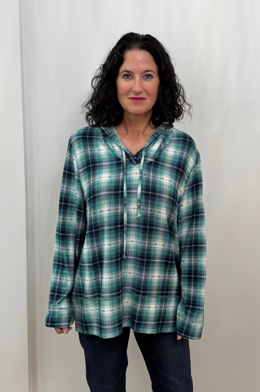 Woman wearing a plaid hoodie and dark pants against a plain background