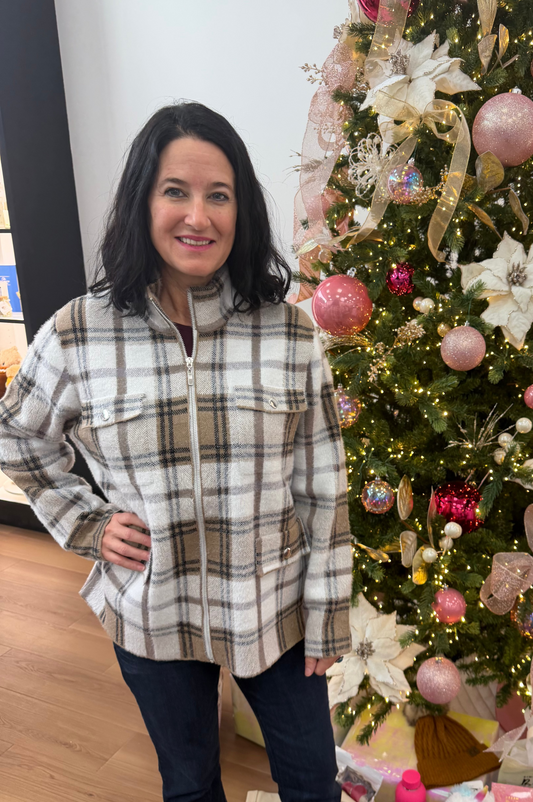 Woman standing in front of a decorated Christmas tree with presents underneath.