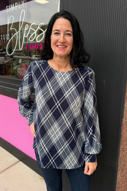 Woman wearing a plaid shirt standing outside a store with a pink and black sign.
