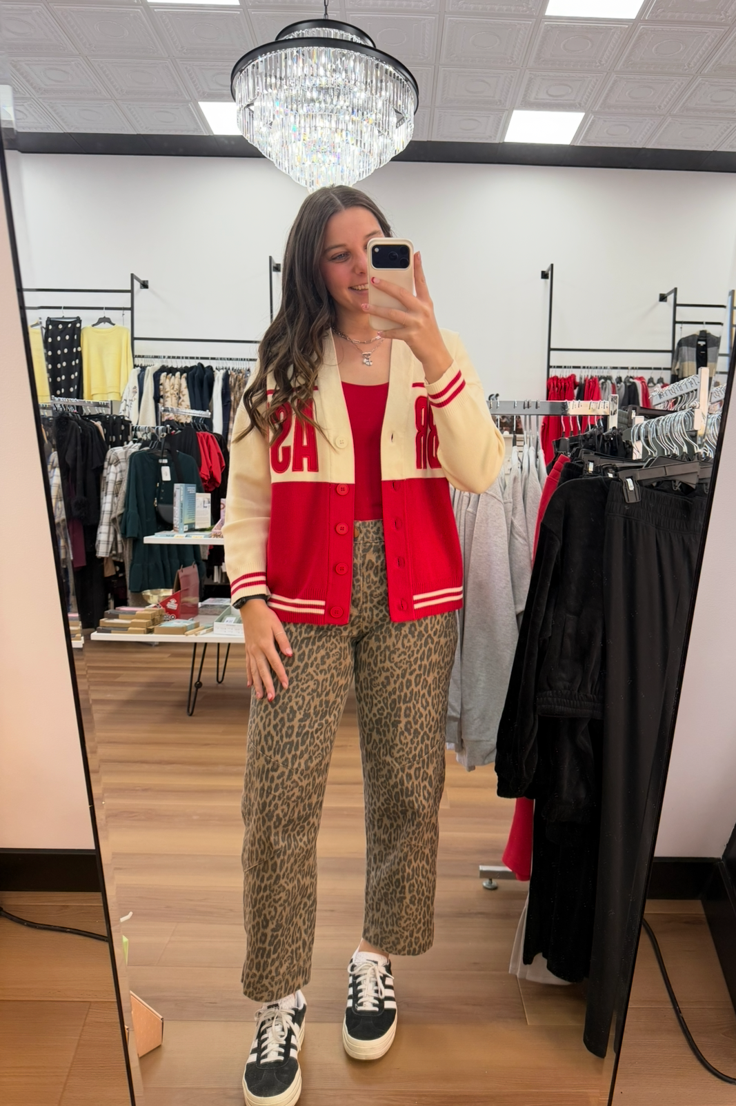 Person wearing a red and white jacket with a yellow shirt, patterned pants, and black sneakers in a store setting.