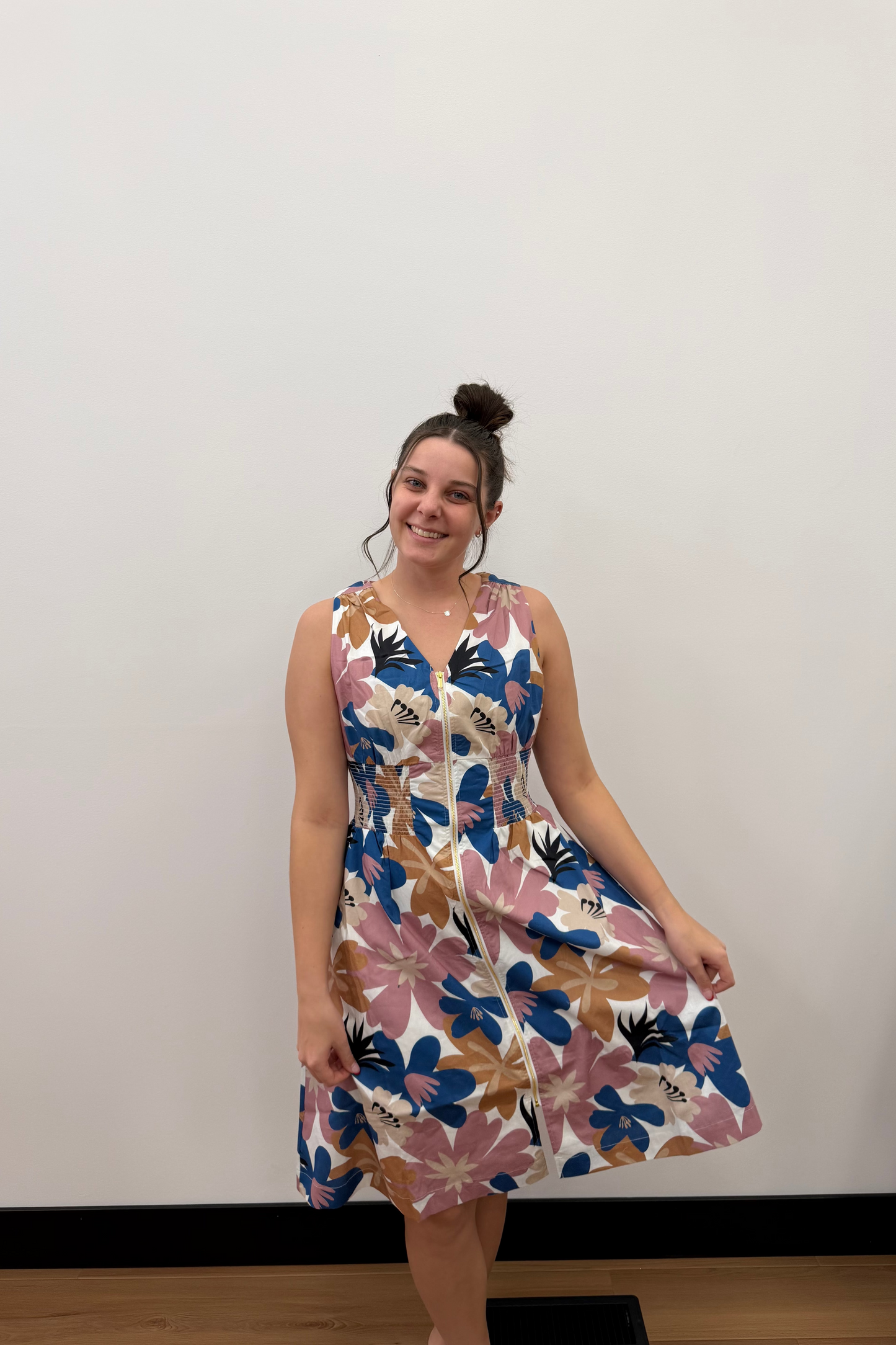 Woman wearing a floral dress against a plain wall