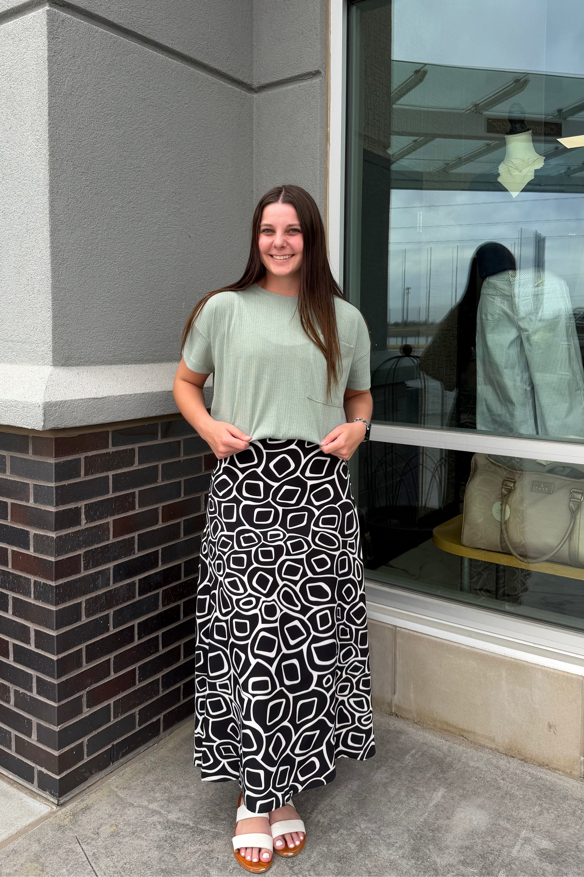 Woman standing outside a store with a window display.