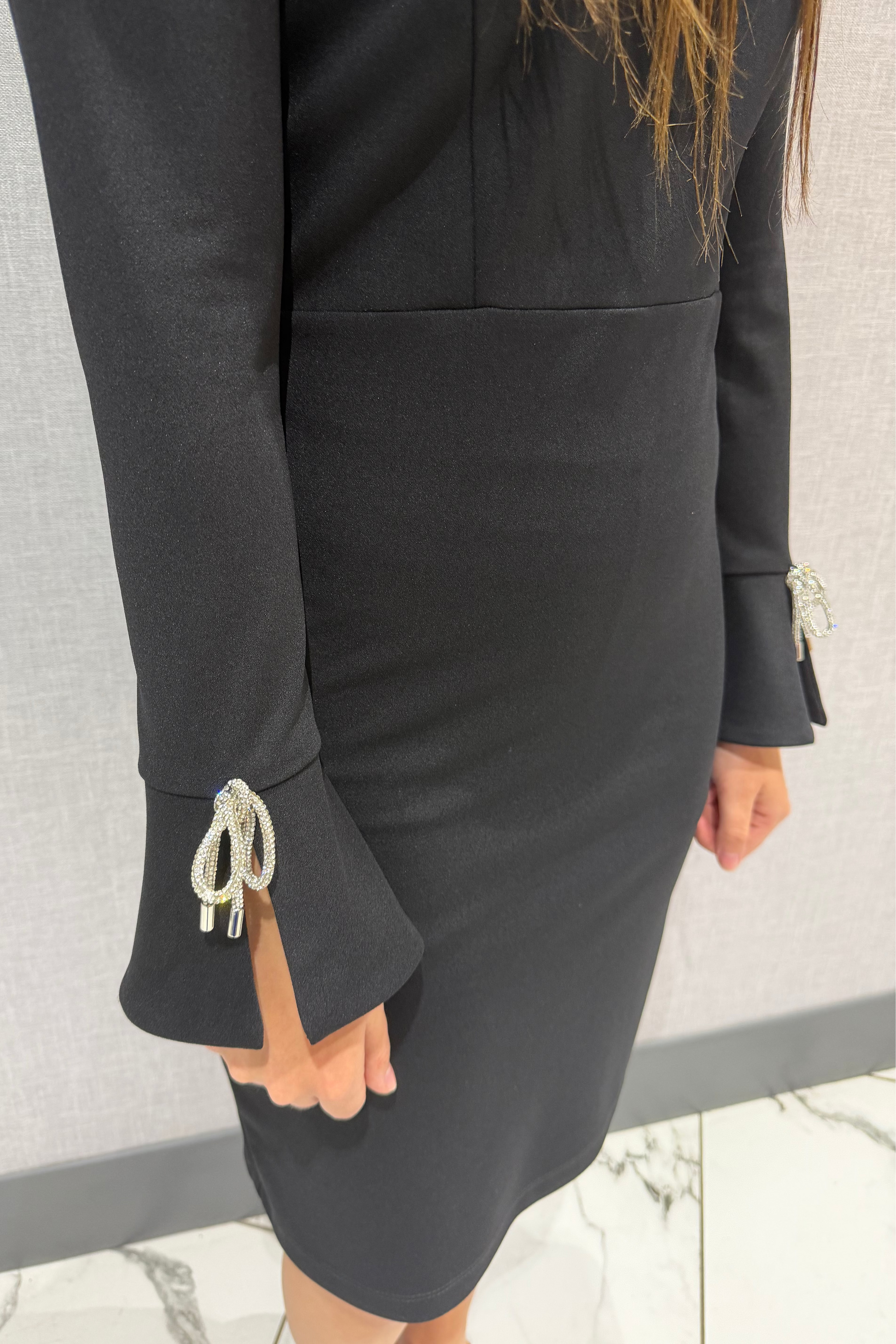 Black dress with decorative cuffs on a neutral background