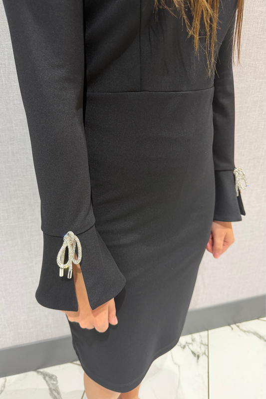 Black dress with decorative cuffs on a neutral background