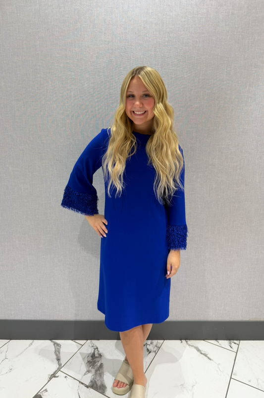 Woman wearing a blue dress standing against a plain background