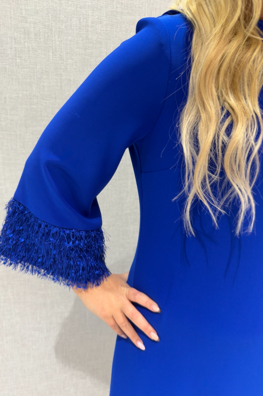 Blue dress with fringed cuffs worn by a person against a neutral background