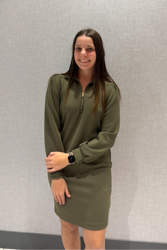 Woman wearing a green dress standing against a plain background