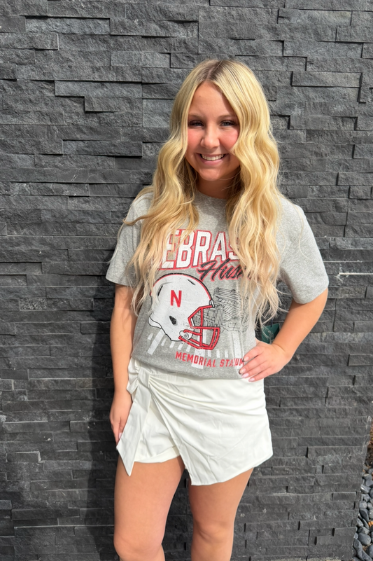 Woman wearing a gray t-shirt with a graphic design against a stone wall.