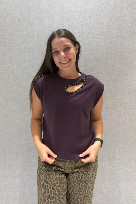 Woman wearing a dark purple top and patterned pants against a plain background