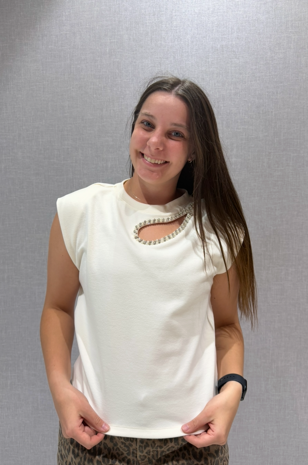 Woman wearing a white sleeveless top against a plain background