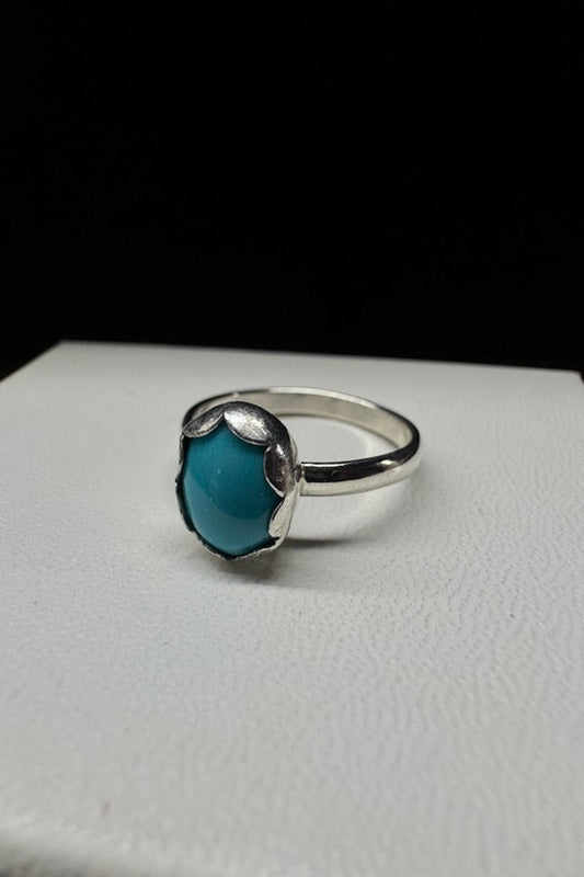 Silver ring with a blue stone on a white surface