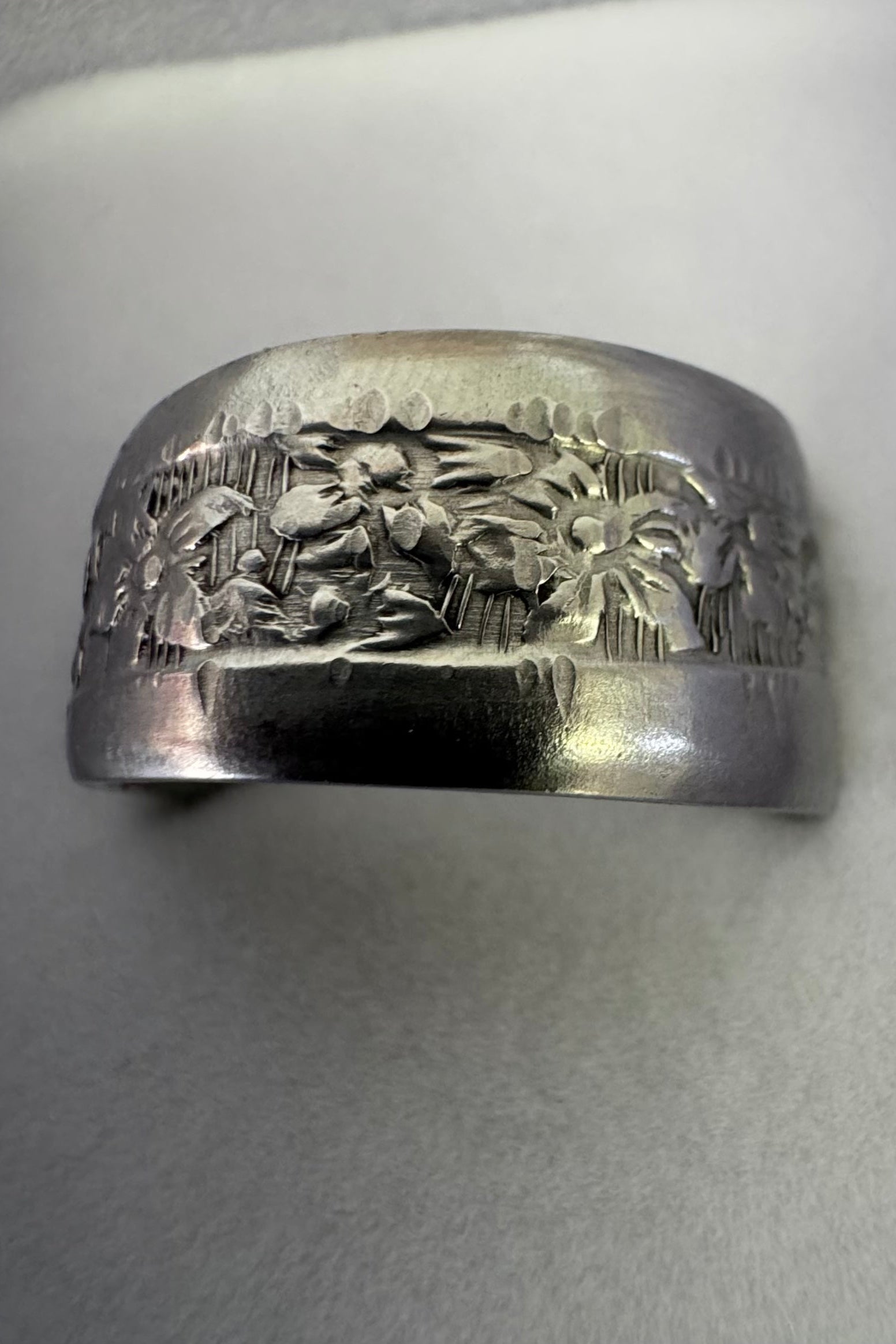 Silver ring with floral design on a white background