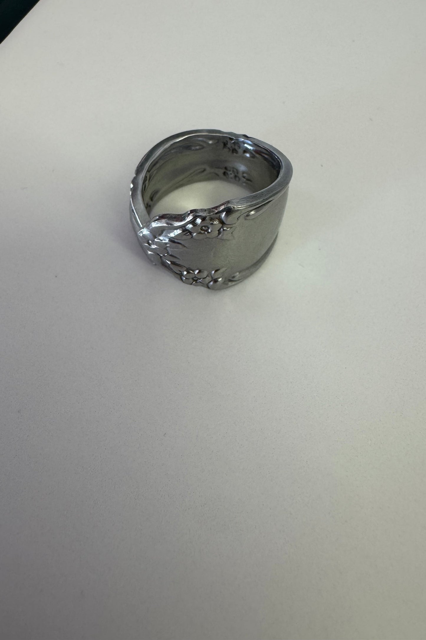 Silver ring with intricate design on a light gray background