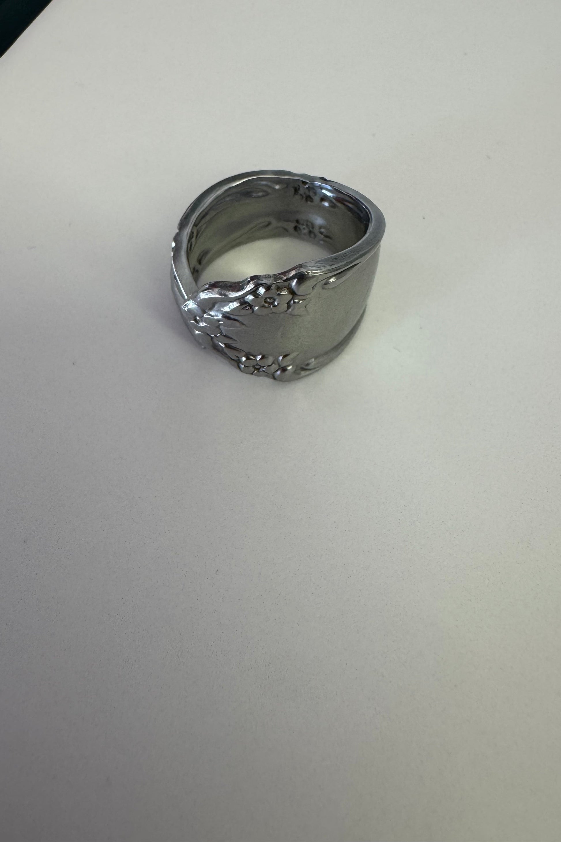 Silver ring with intricate design on a light gray background