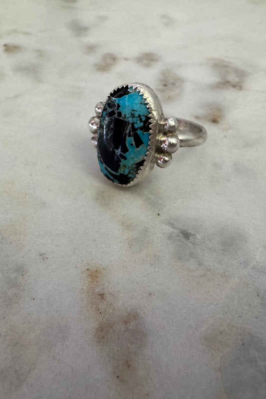 Silver ring with a blue stone on a marble surface