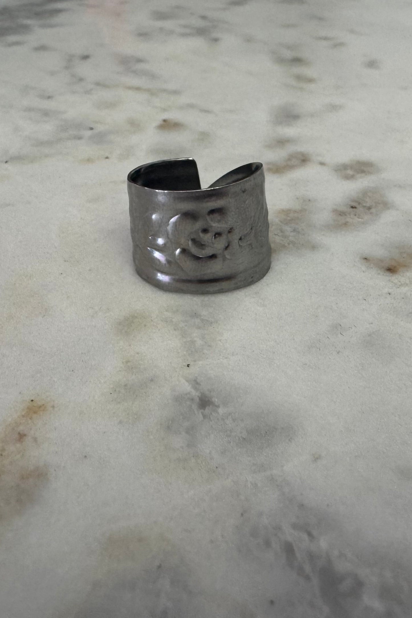 Silver ring with a floral design on a marble surface