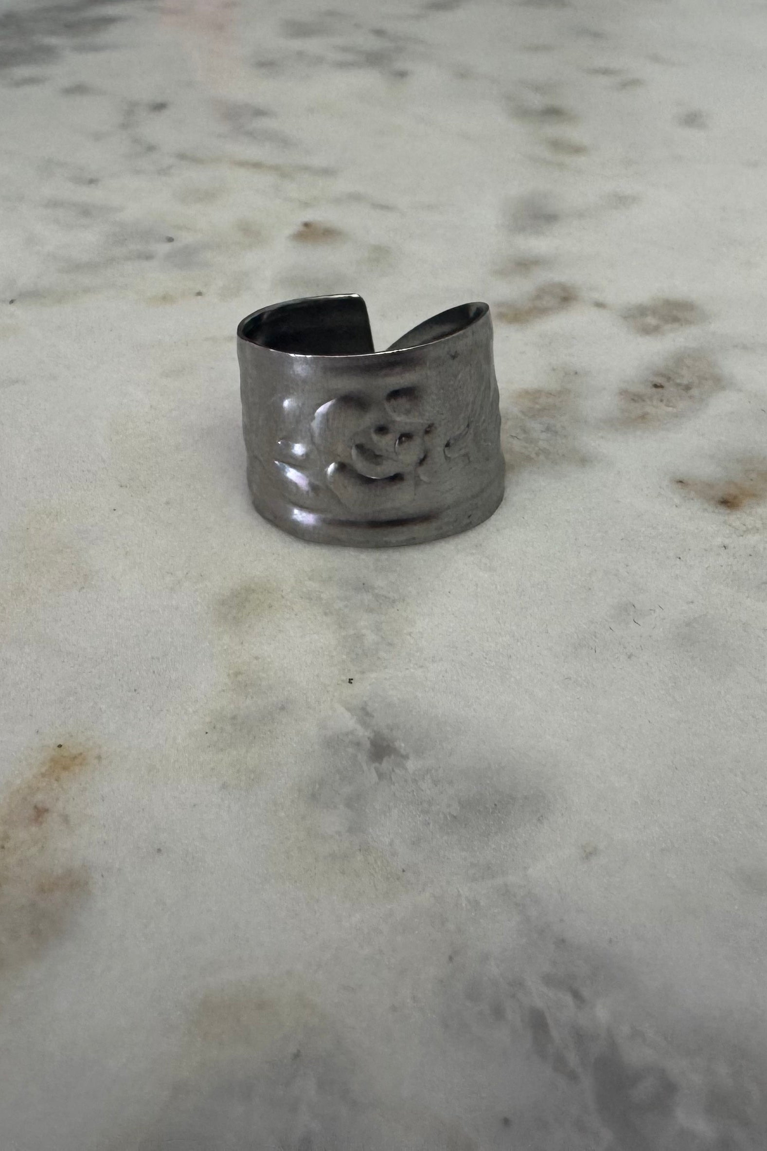 Silver ring with a floral design on a marble surface