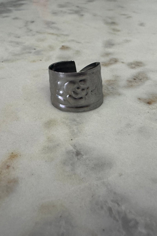 Silver ring with a floral design on a marble surface