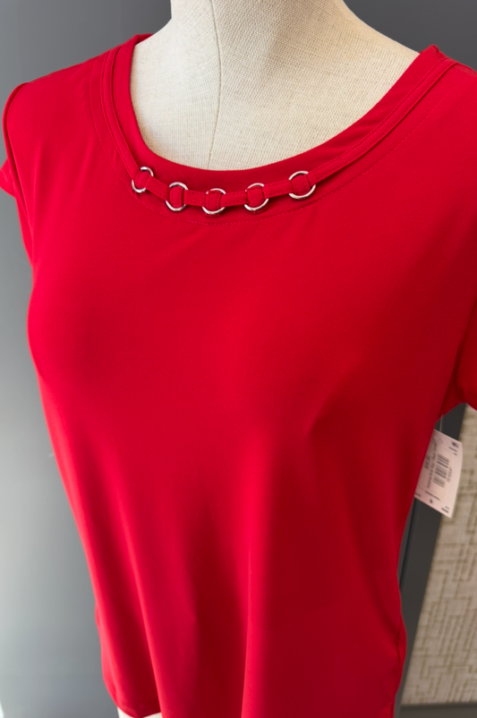 Red top with decorative metal rings on a mannequin against a neutral background