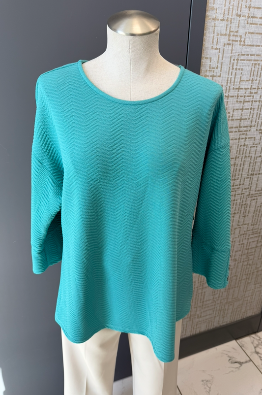 Teal sweater on a mannequin against a neutral background