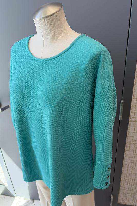 Teal sweater on a mannequin against a neutral background