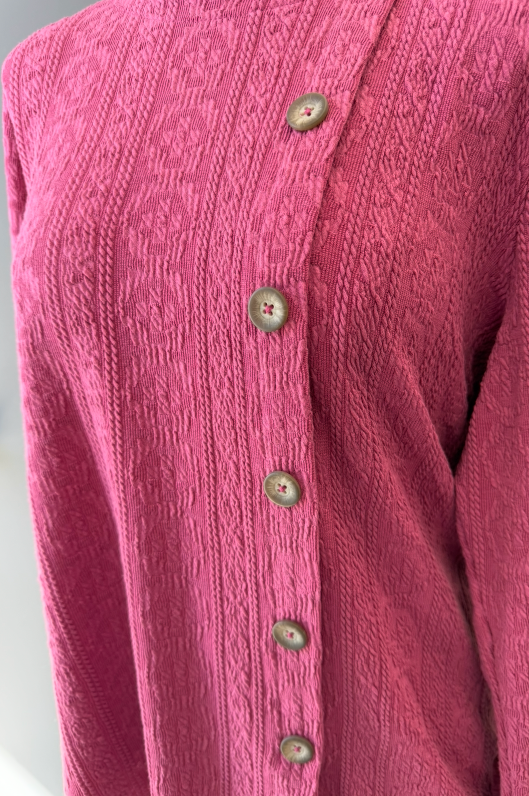 Close-up of a pink textured shirt with buttons on a white background