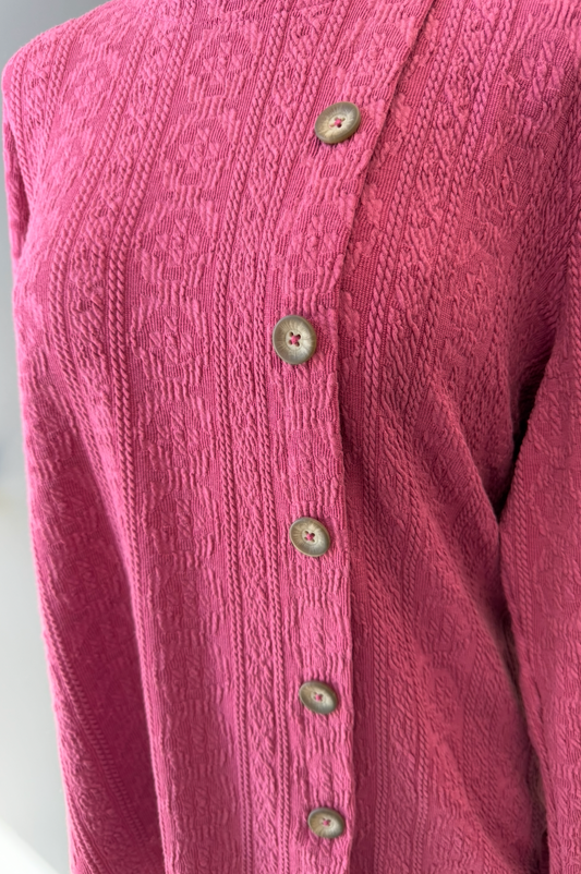 Close-up of a pink textured shirt with buttons on a white background