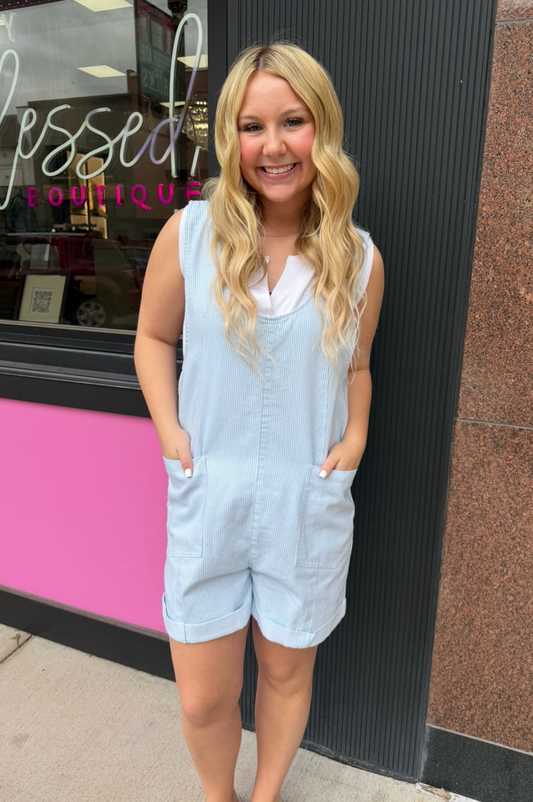 Woman in a light blue romper standing outside a store with a pink interior.