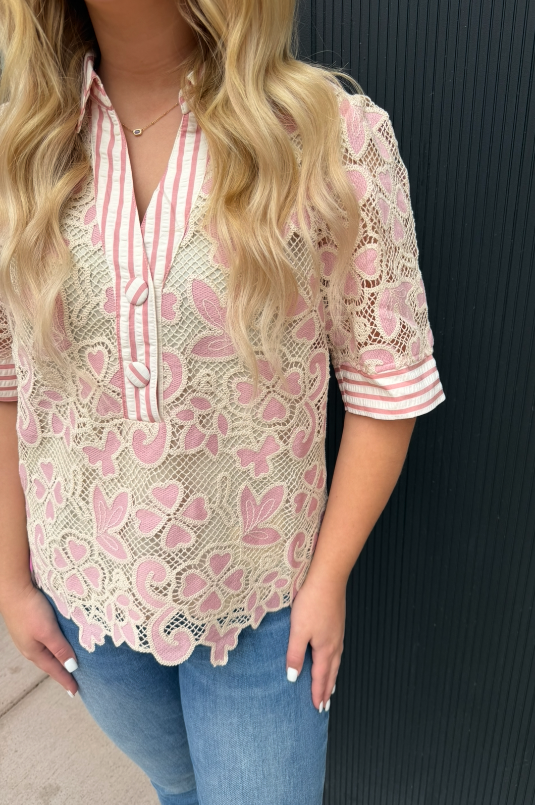 Woman wearing a pink lace blouse with a black background