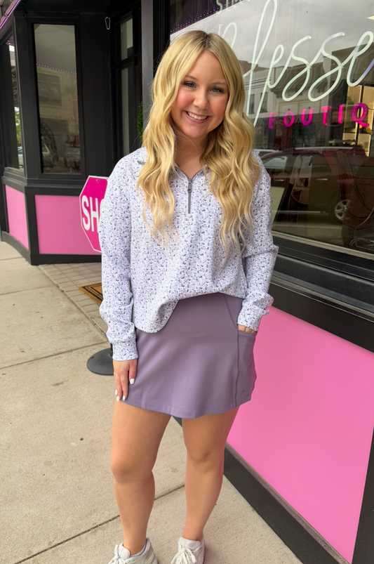 Woman standing on a sidewalk in front of a pink building with a sign.