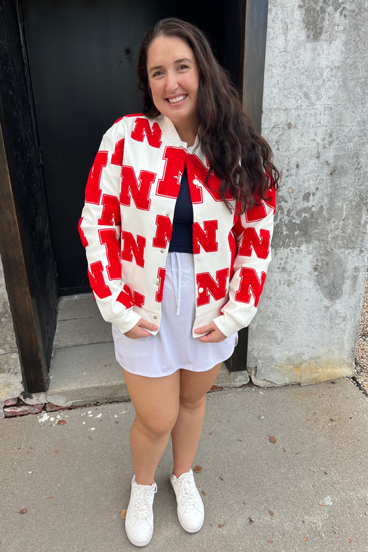 Woman wearing a red and white patterned jacket standing outside a building.
