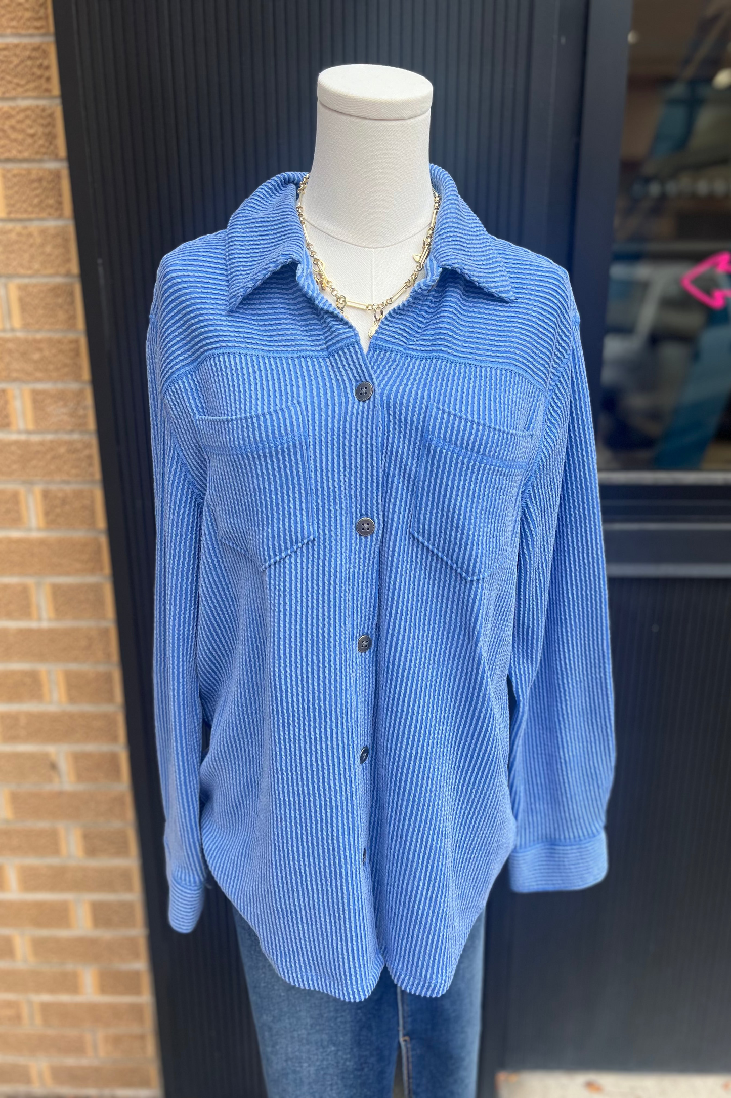 Blue corduroy shirt on a mannequin against a brick wall.