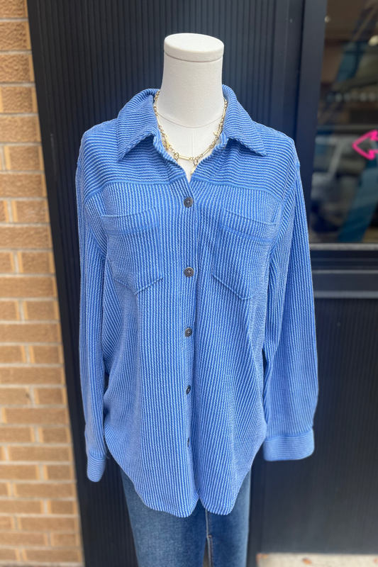 Blue corduroy shirt on a mannequin against a brick wall.