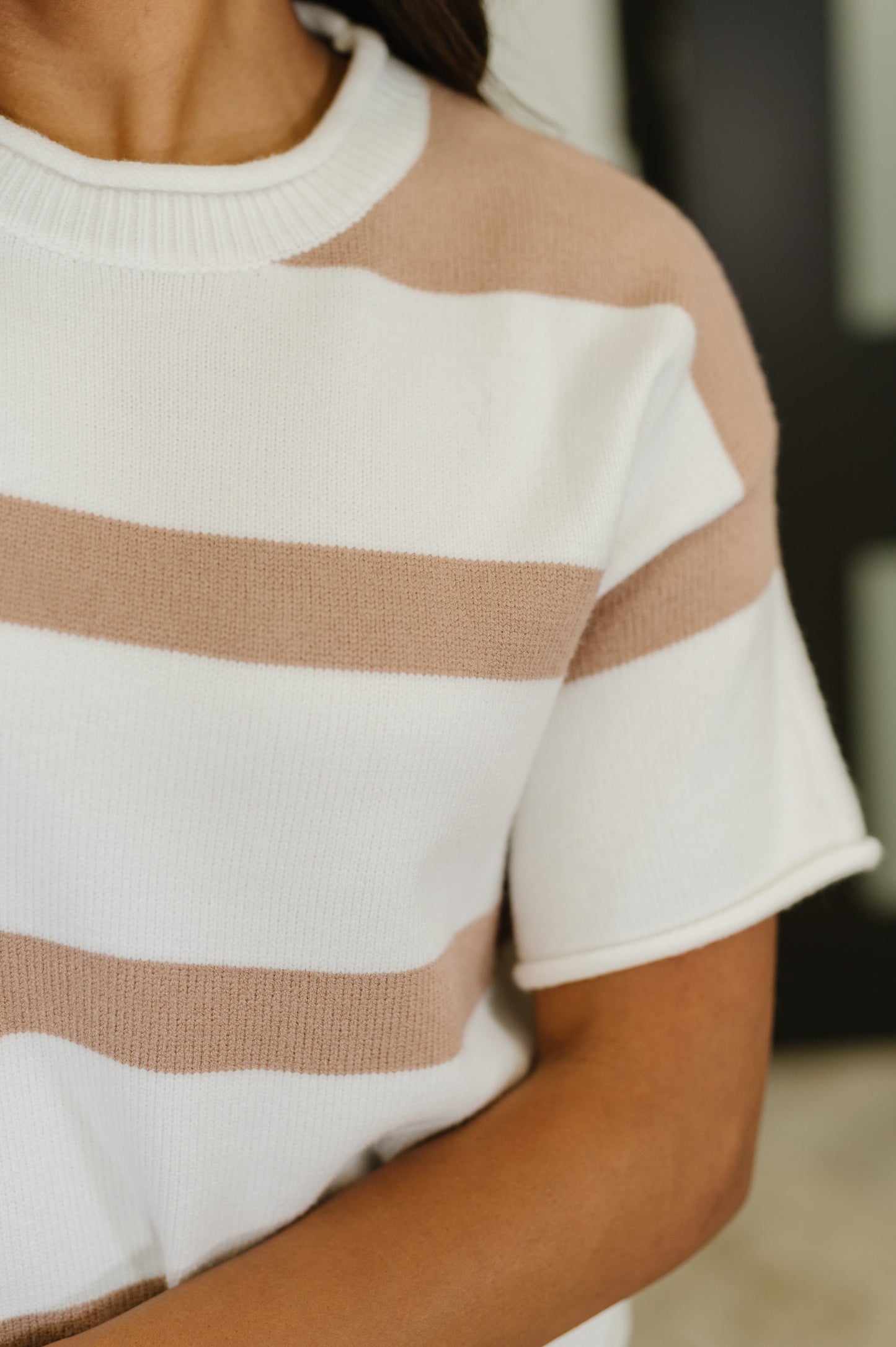Close-up of a person wearing a white and brown striped sweater.