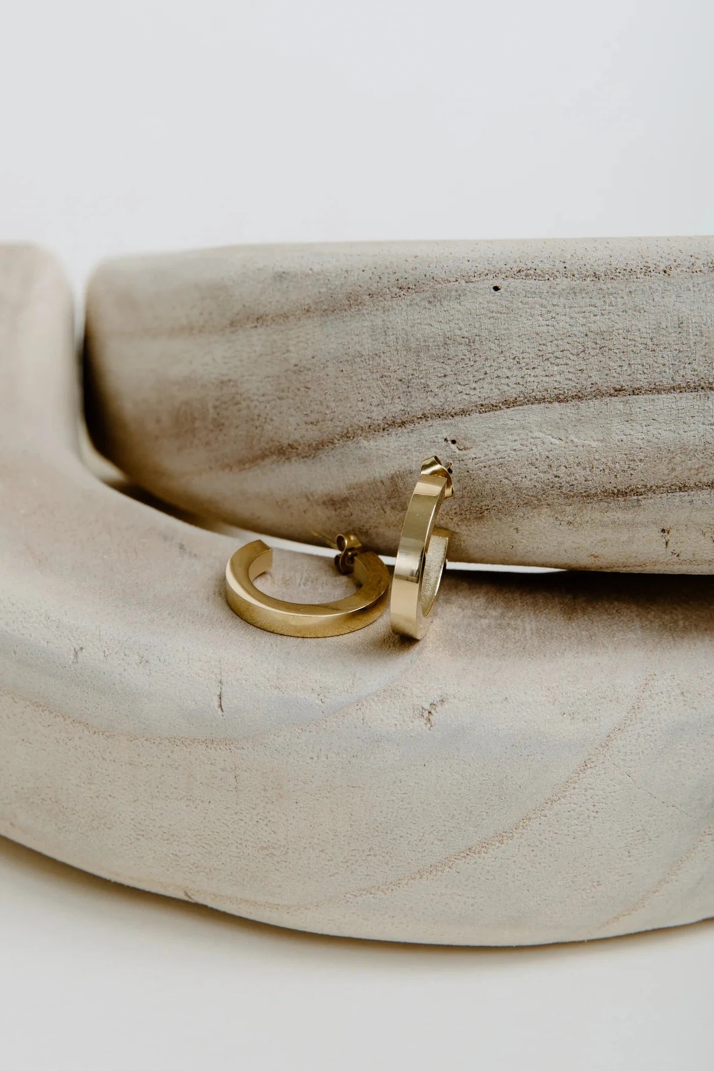 Gold hoop earrings on a wooden surface