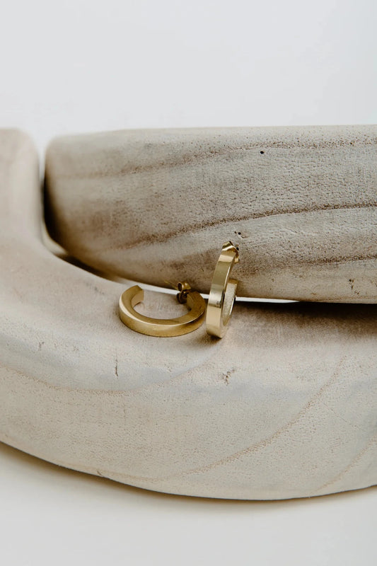 Gold hoop earrings on a wooden surface